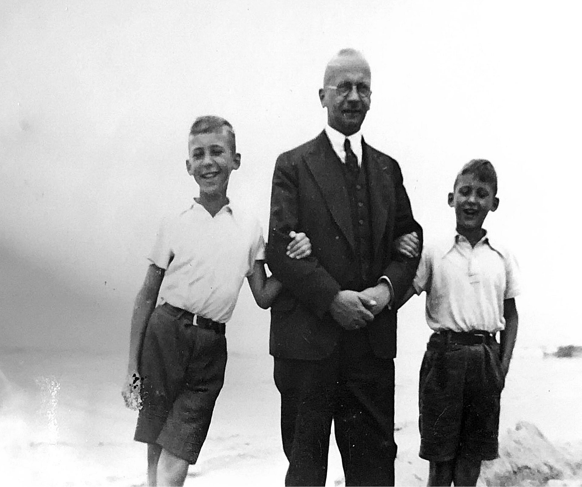Historisches Foto eines Mannes im Anzug, links und rechts flankiert von zwei Jungen in kurzen Hosen