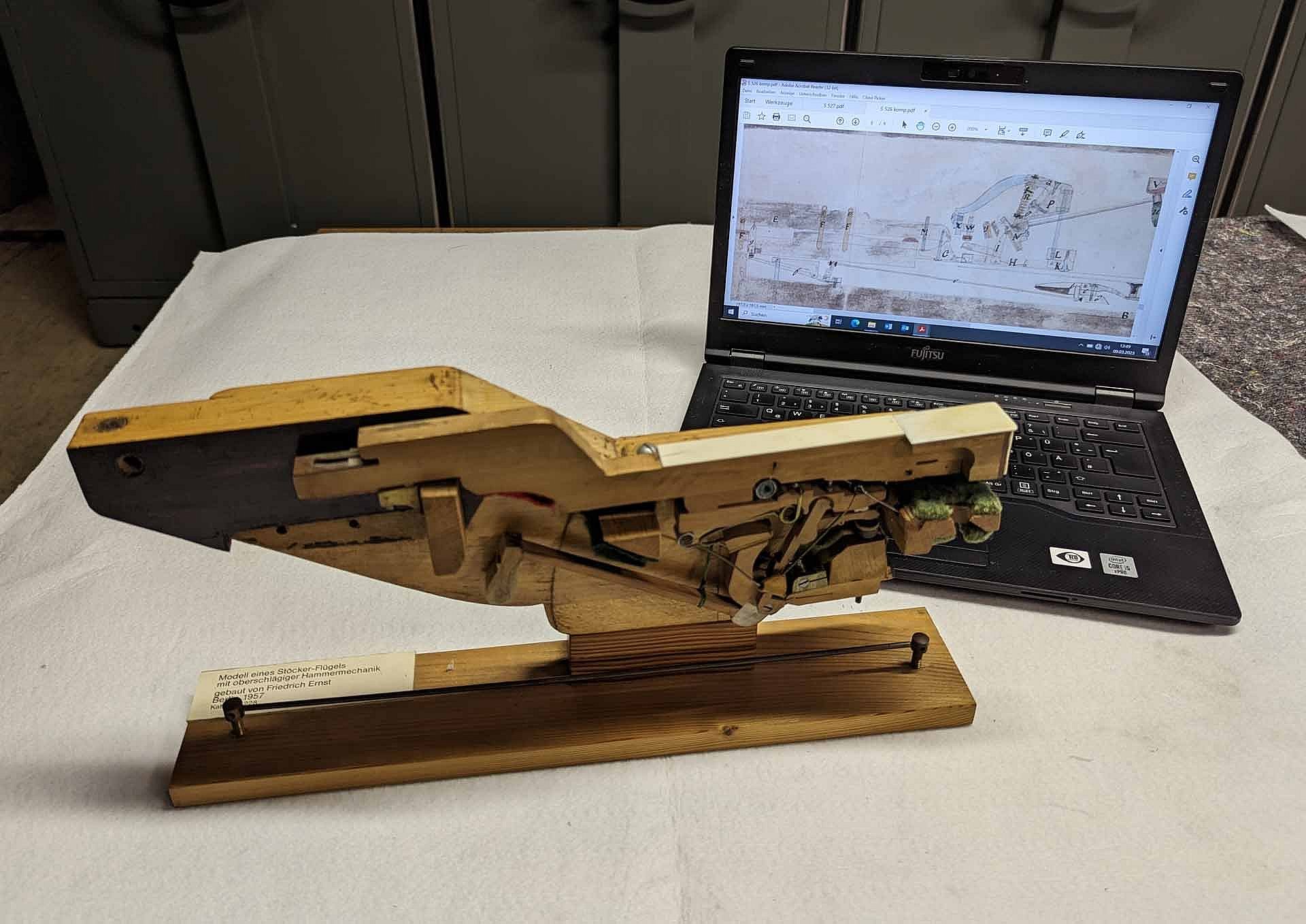 Flügelmechanik auf einem Tisch, daneben auf dem Laptopbildschirm die dazugehörige Zeichnung
