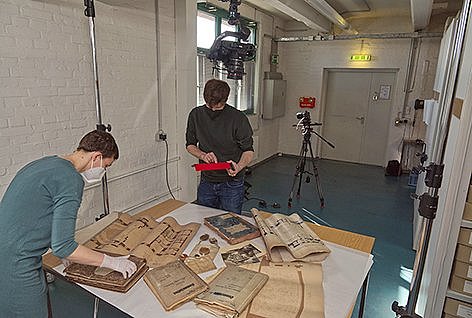 Zwei Personen begutachten historische Schriften an einem großen Tisch.
