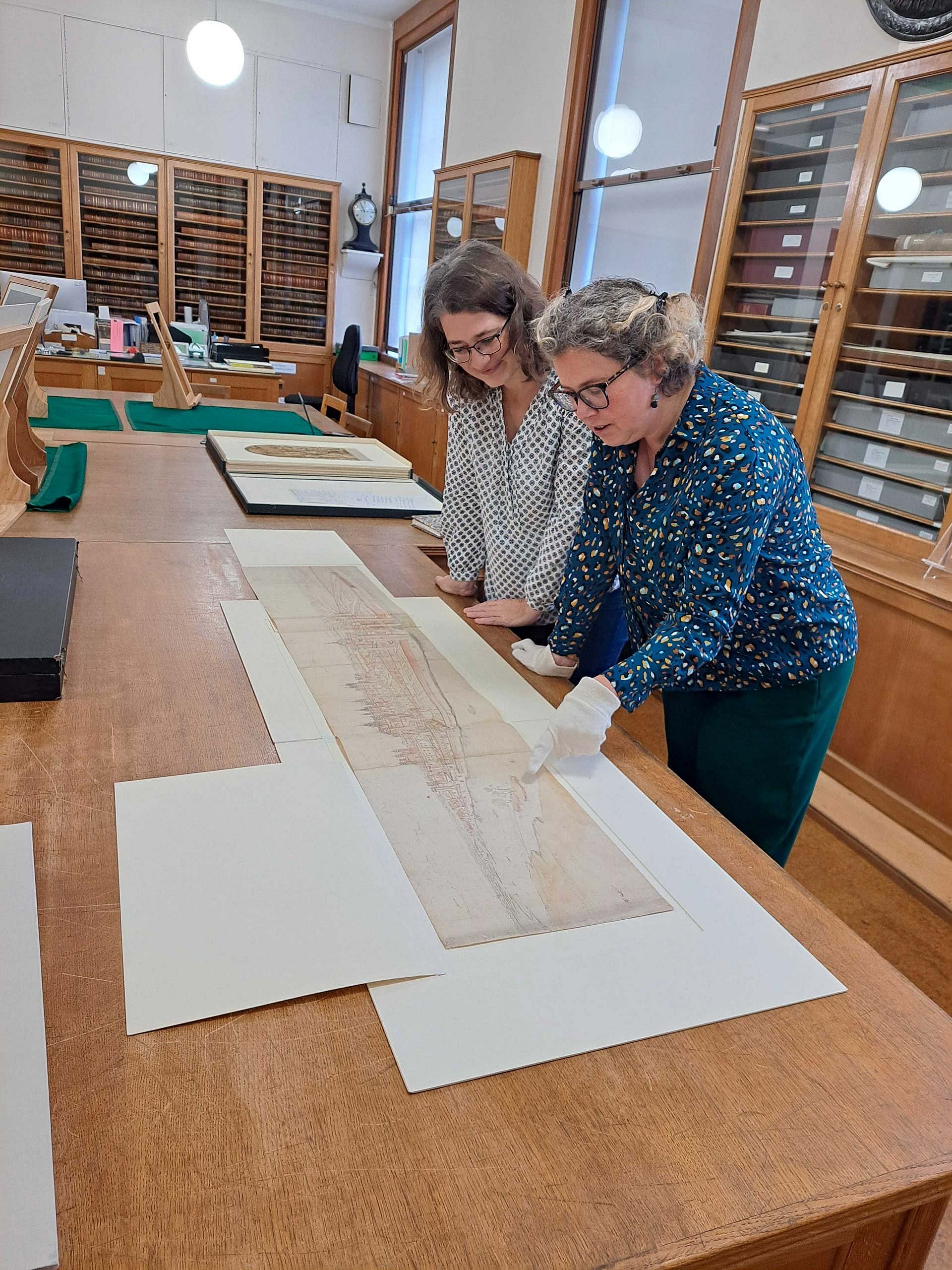 Zwei Frauen betrachten Zeichnungen im Studiensaal