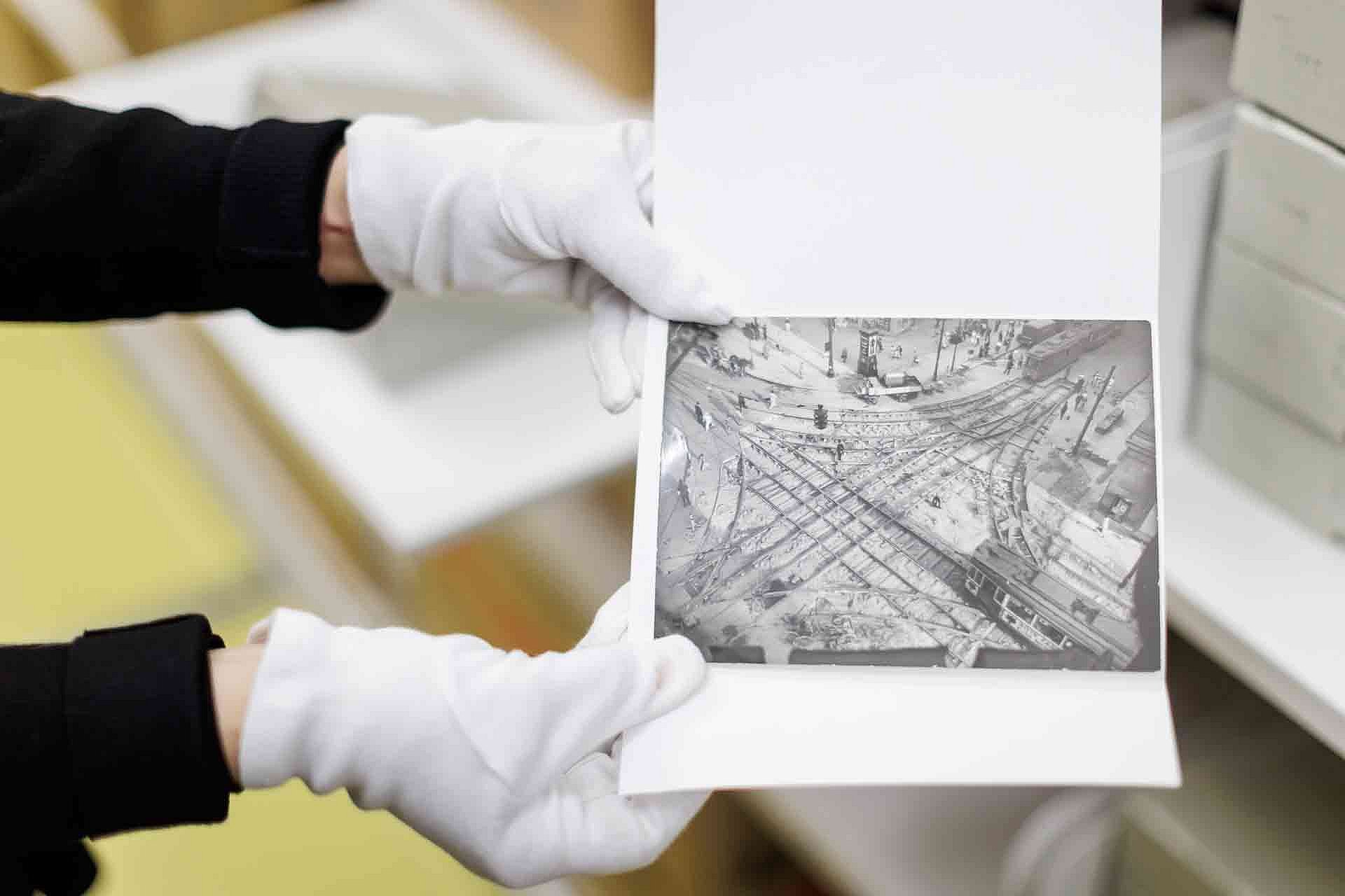Eine Person mit weißen Handschuhen zeigt eine Schwarz-Weiß-Fotografie