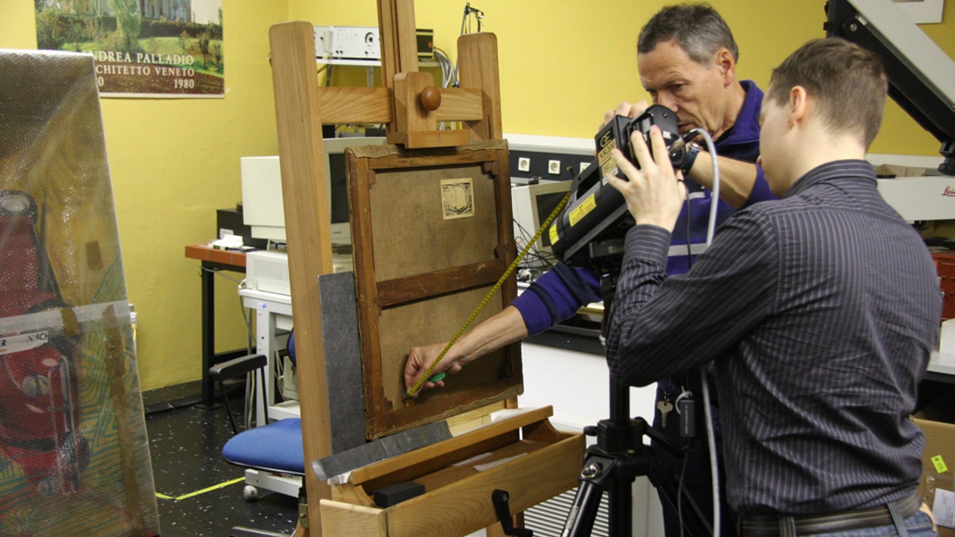 Two men are carrying out a scientific analysis of a picture