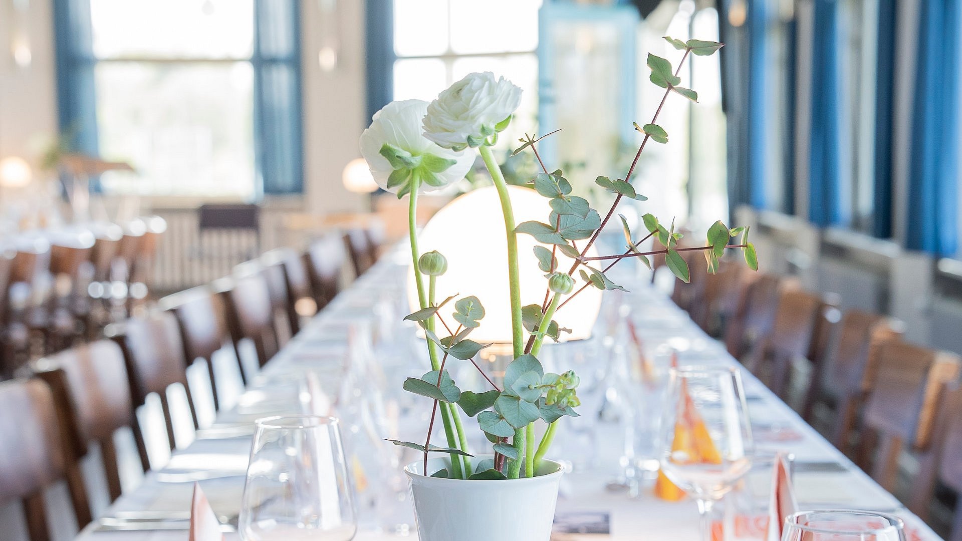 Gedeckter Tafel ohne Besucher mit weißer Porzellanvase im Vordergrund