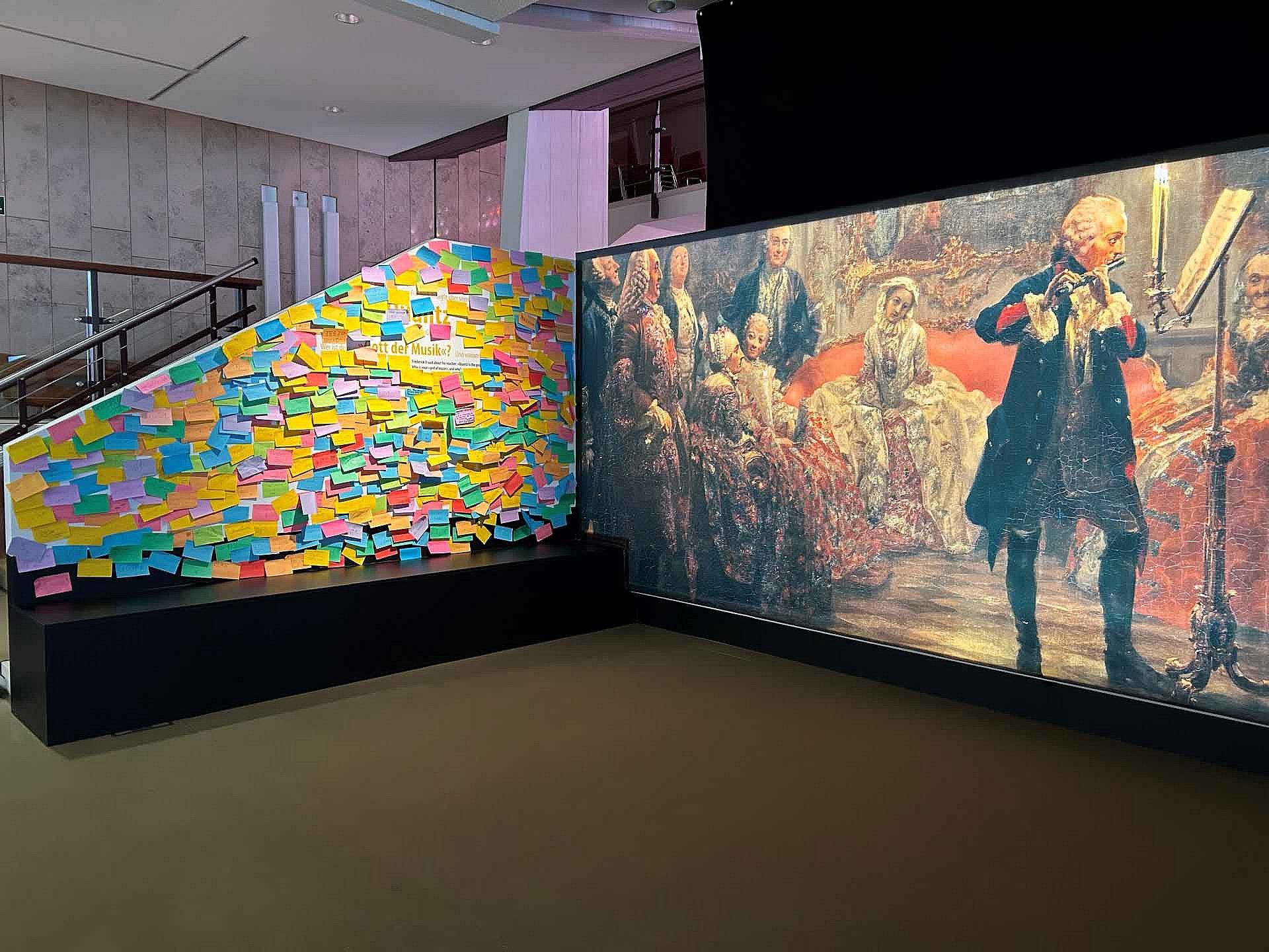 Blick in eine Museumsausstellung: Links mit Post-its beklebte Wand, rechts eine Großprojektion