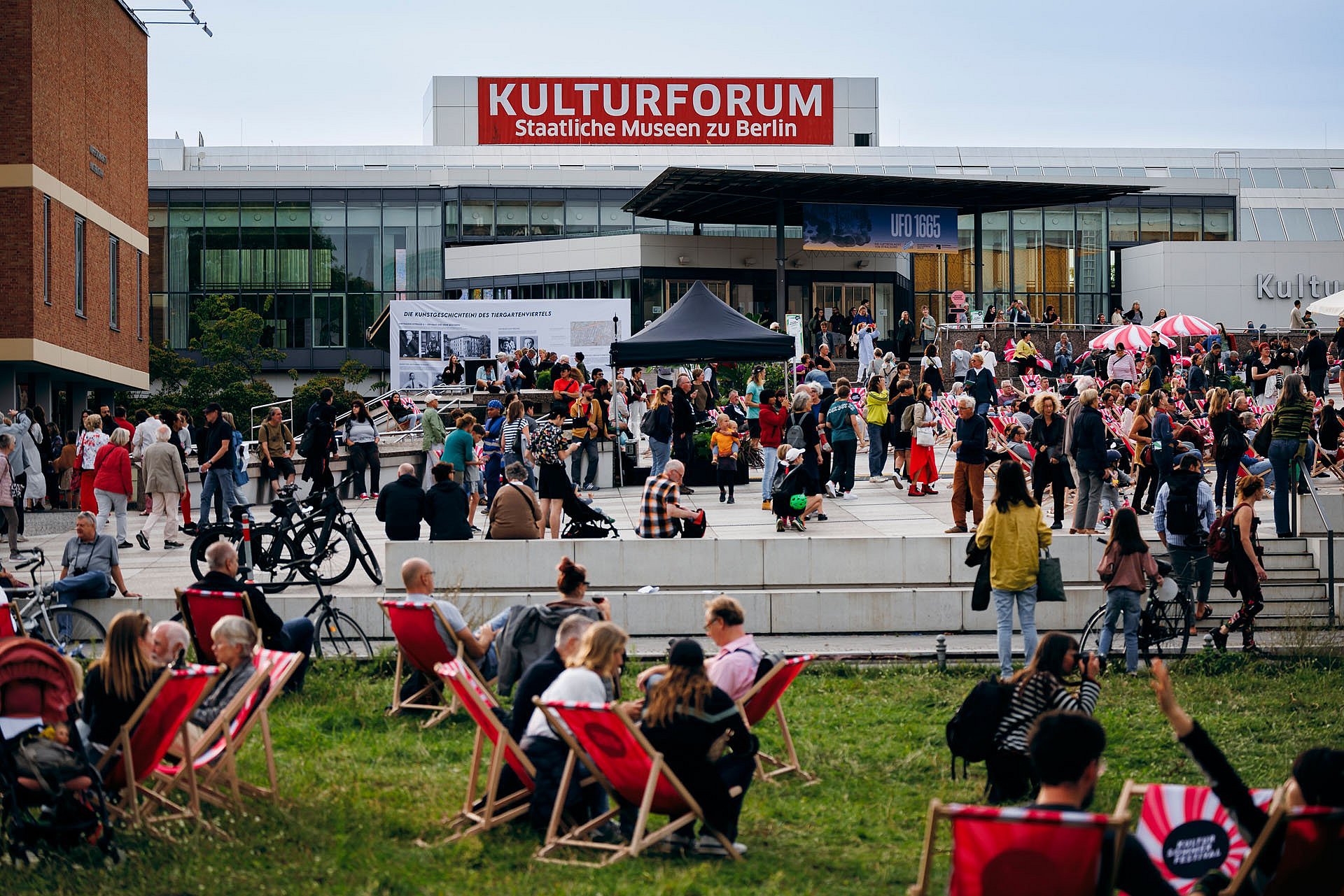 Menschenmengen auf Liegestühlen und vor einem modernen Museum