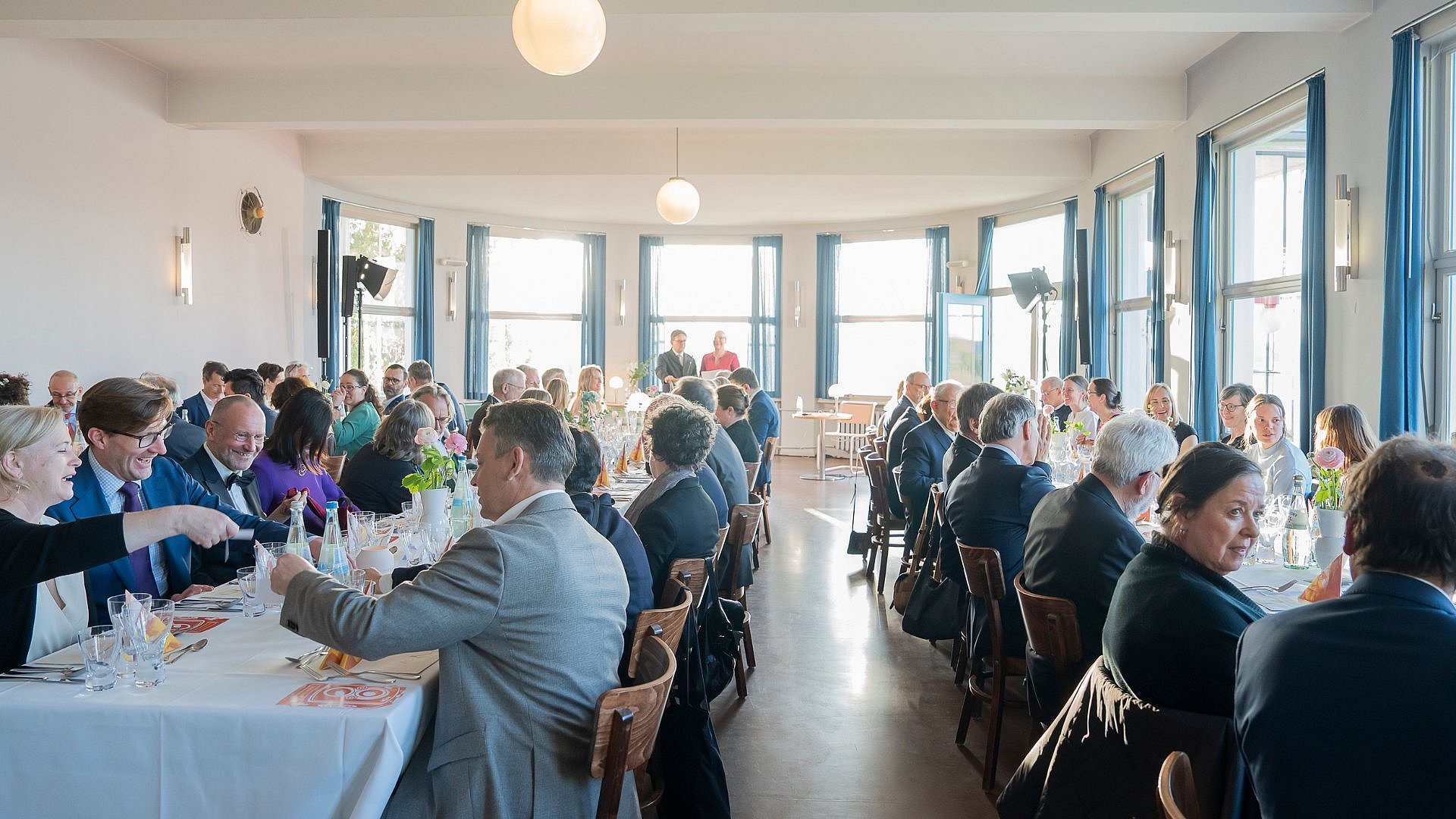 Tischgesellschaft in hellem Raum mit großer Fensterfront