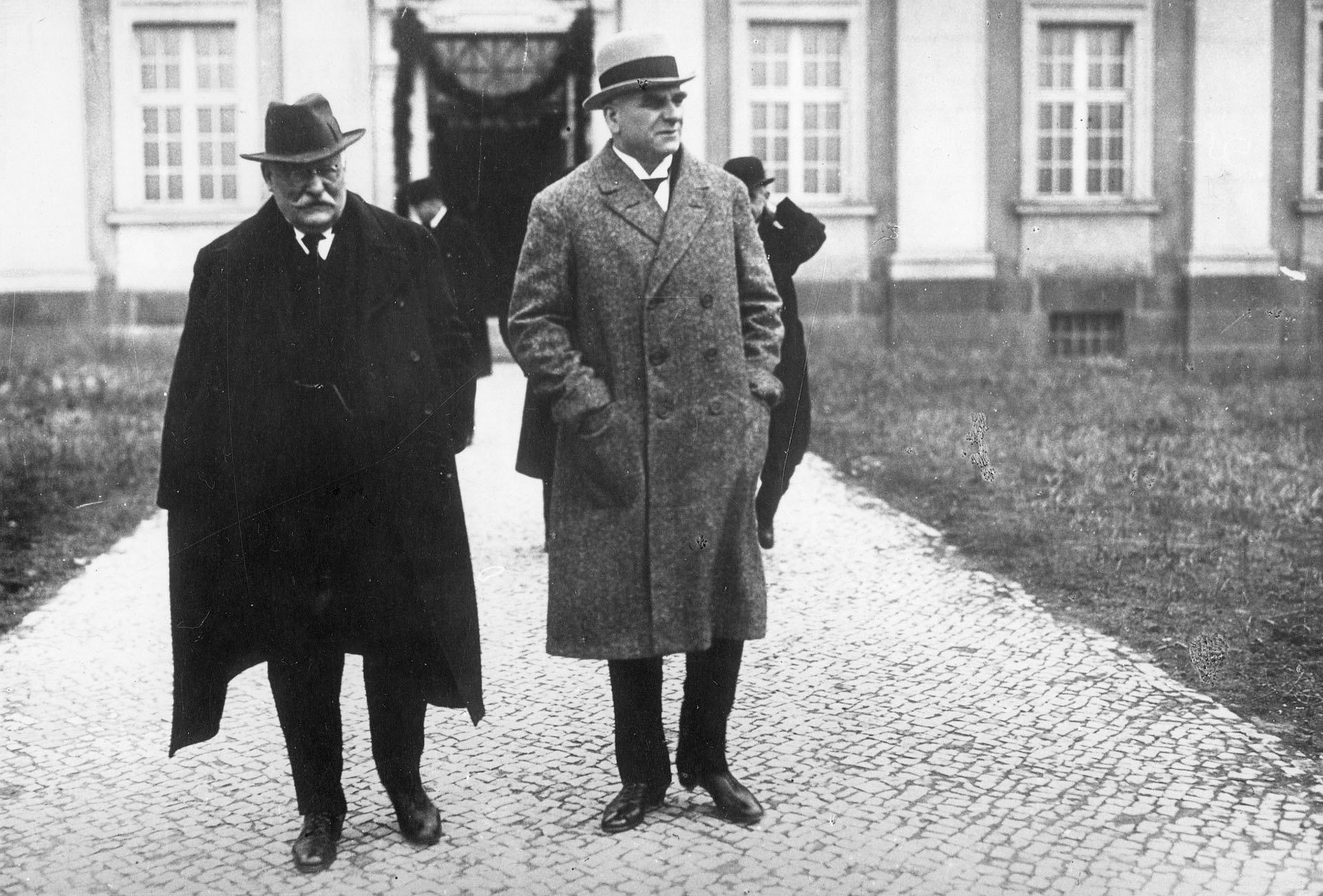 Historisches Foto zweier Männer in Mänteln vor einem Gebäude