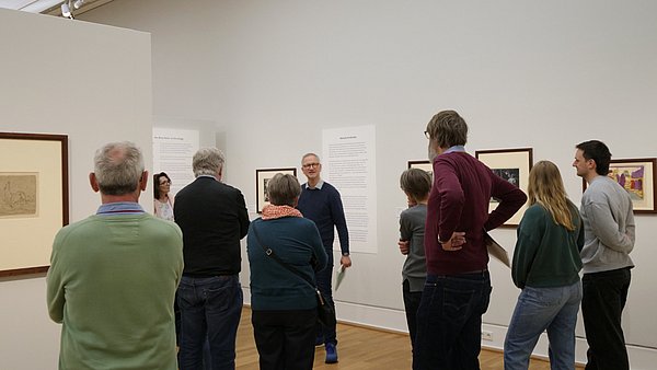 Kurator Andreas Schalhorn eine Menschengruppe in einem Ausstellungsraum