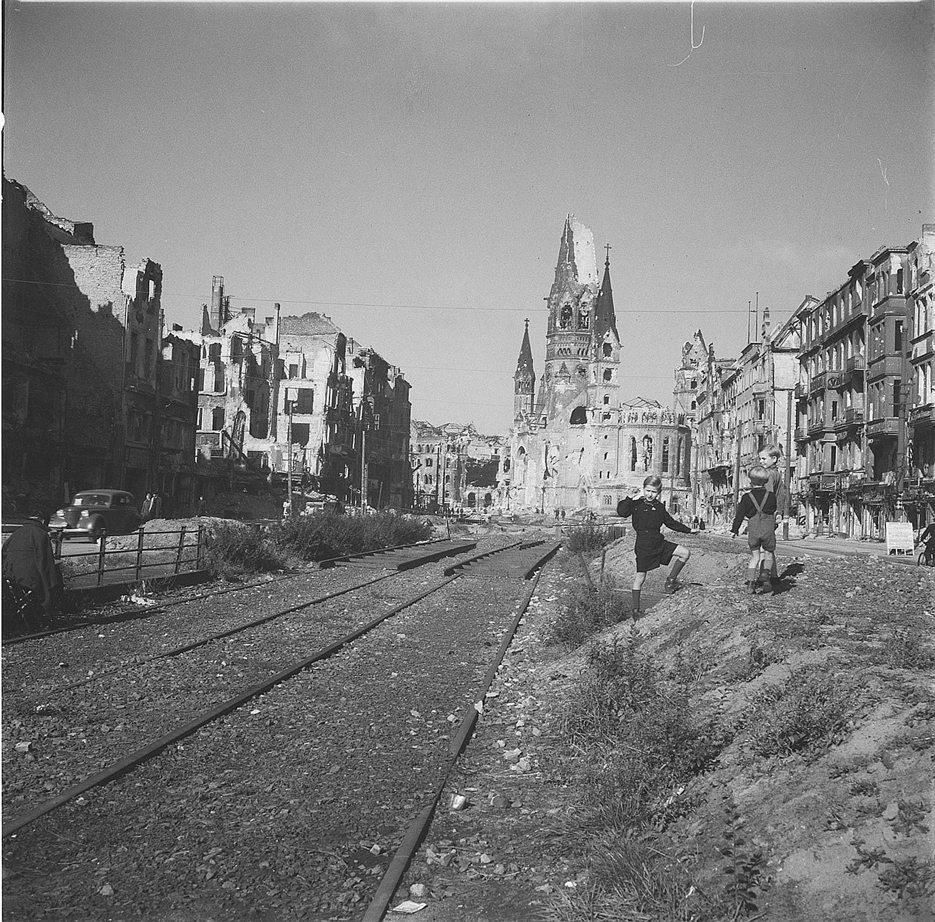 Schwarz-Weiß Foto: Straßenbild mit Kindergruppe und Ruine der Kaiser-Wilhelm-Gedächtniskirche, Berlin