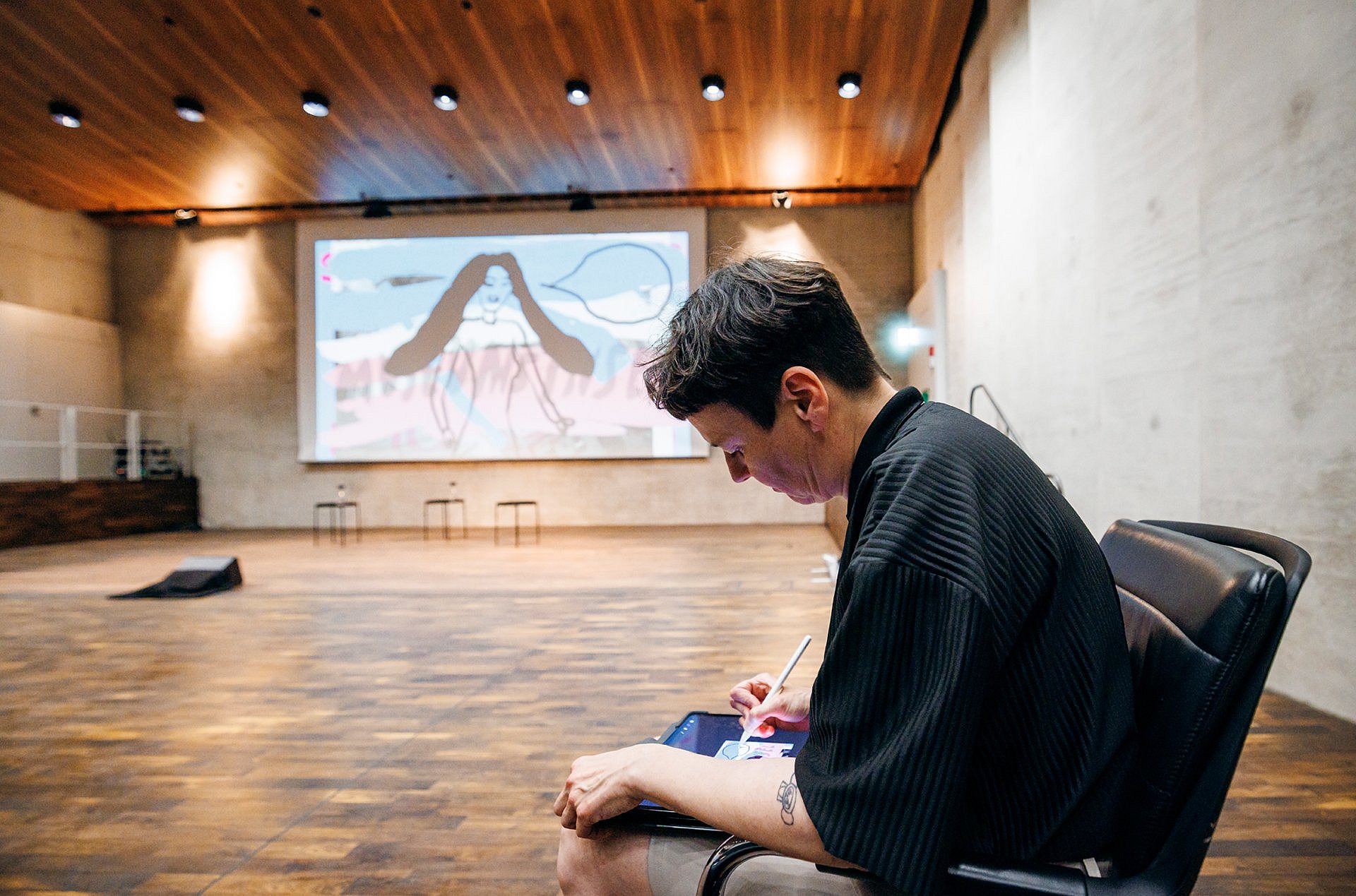 Eine Person zeichnet auf einem Tablet, die Zeichnung wird live auf die Leinwand im Hintergrund übertragen