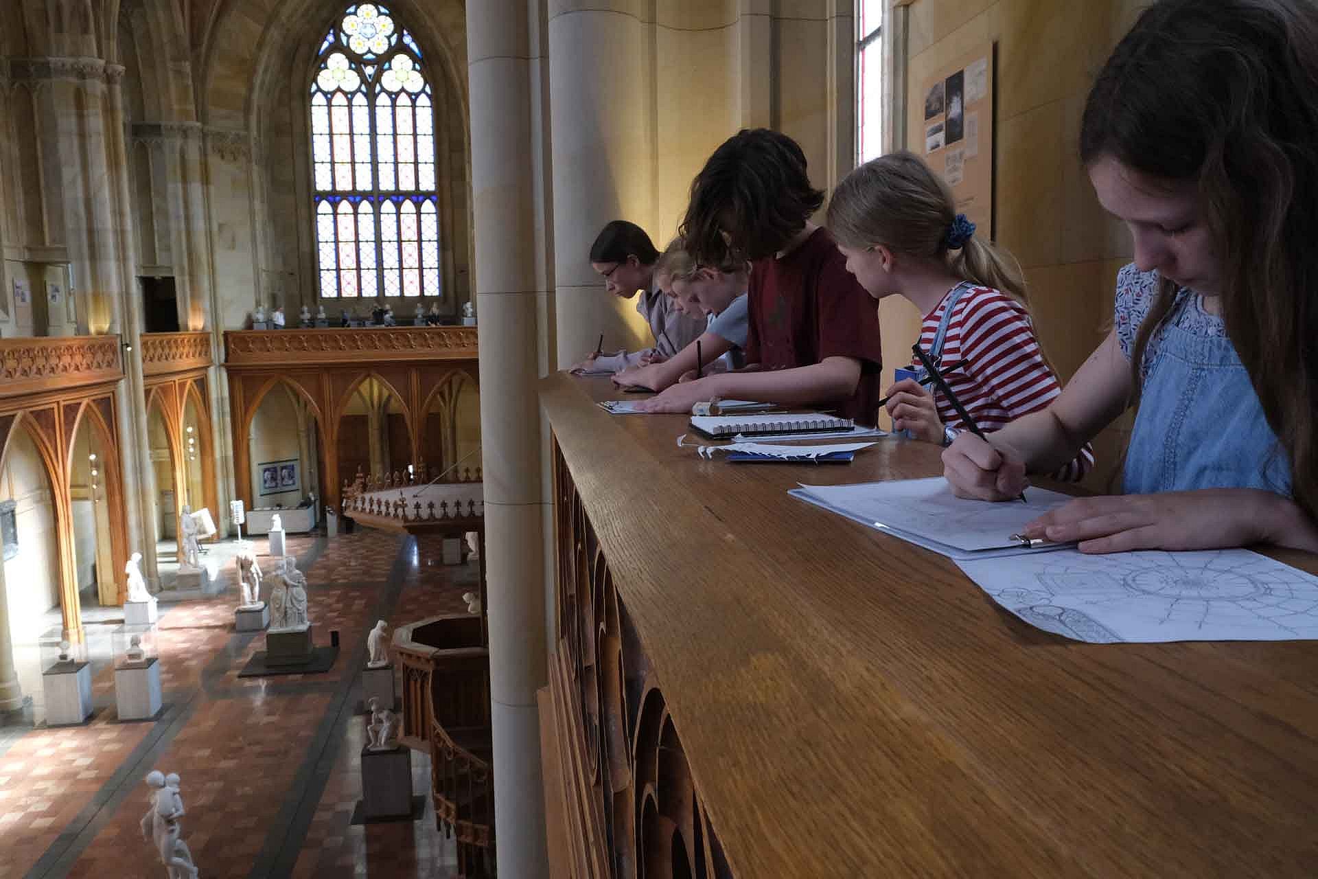 Kinder zeichnen in einem Kircheninnenraum