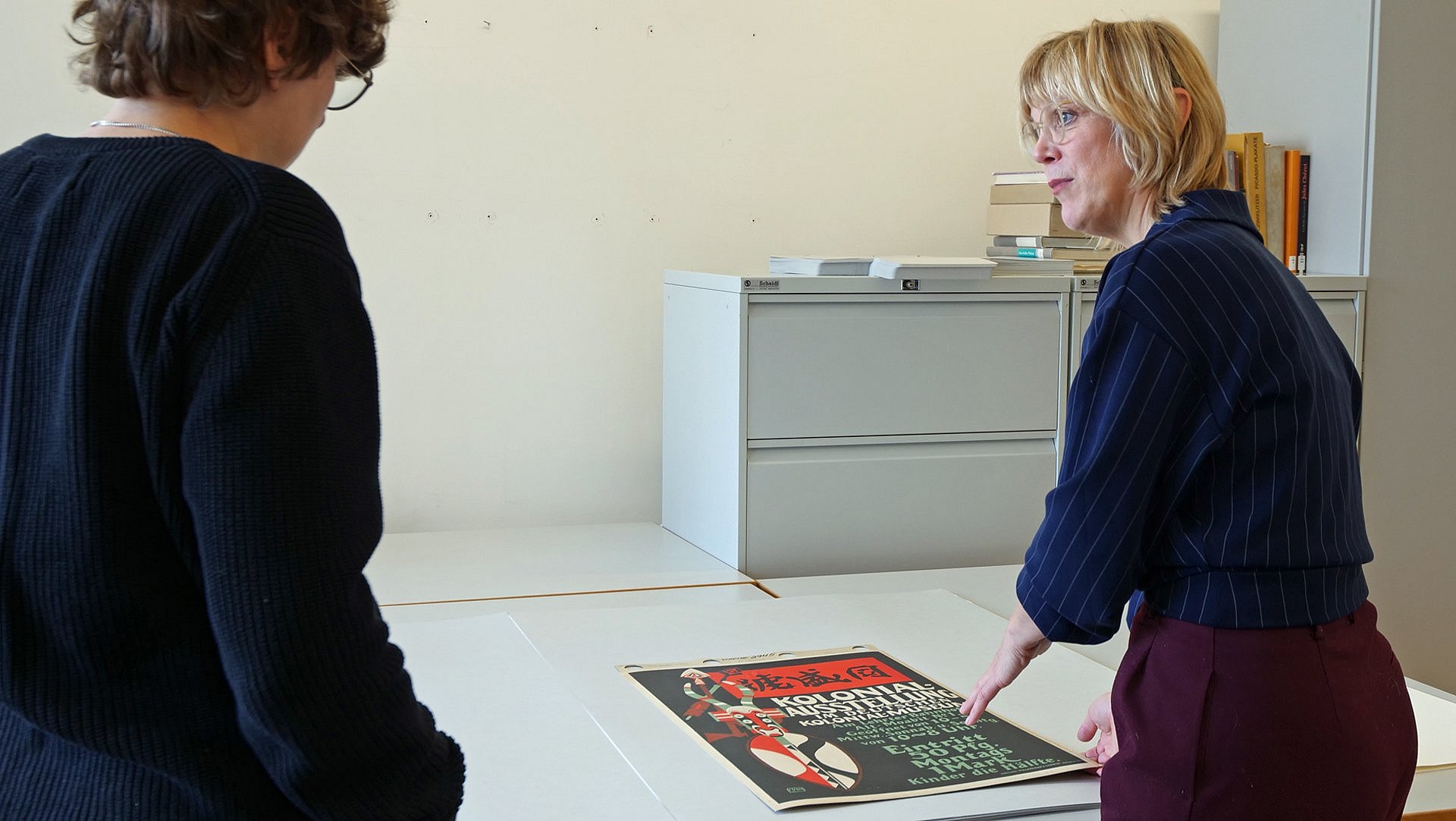 Eine Person erklärt einer anderen Person ein Plakat