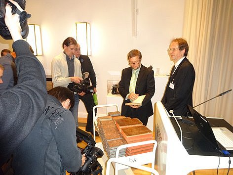 Mehrere Menschen betrachten Bücher auf einem Bücherwagen und werden dabei fotografiert.
