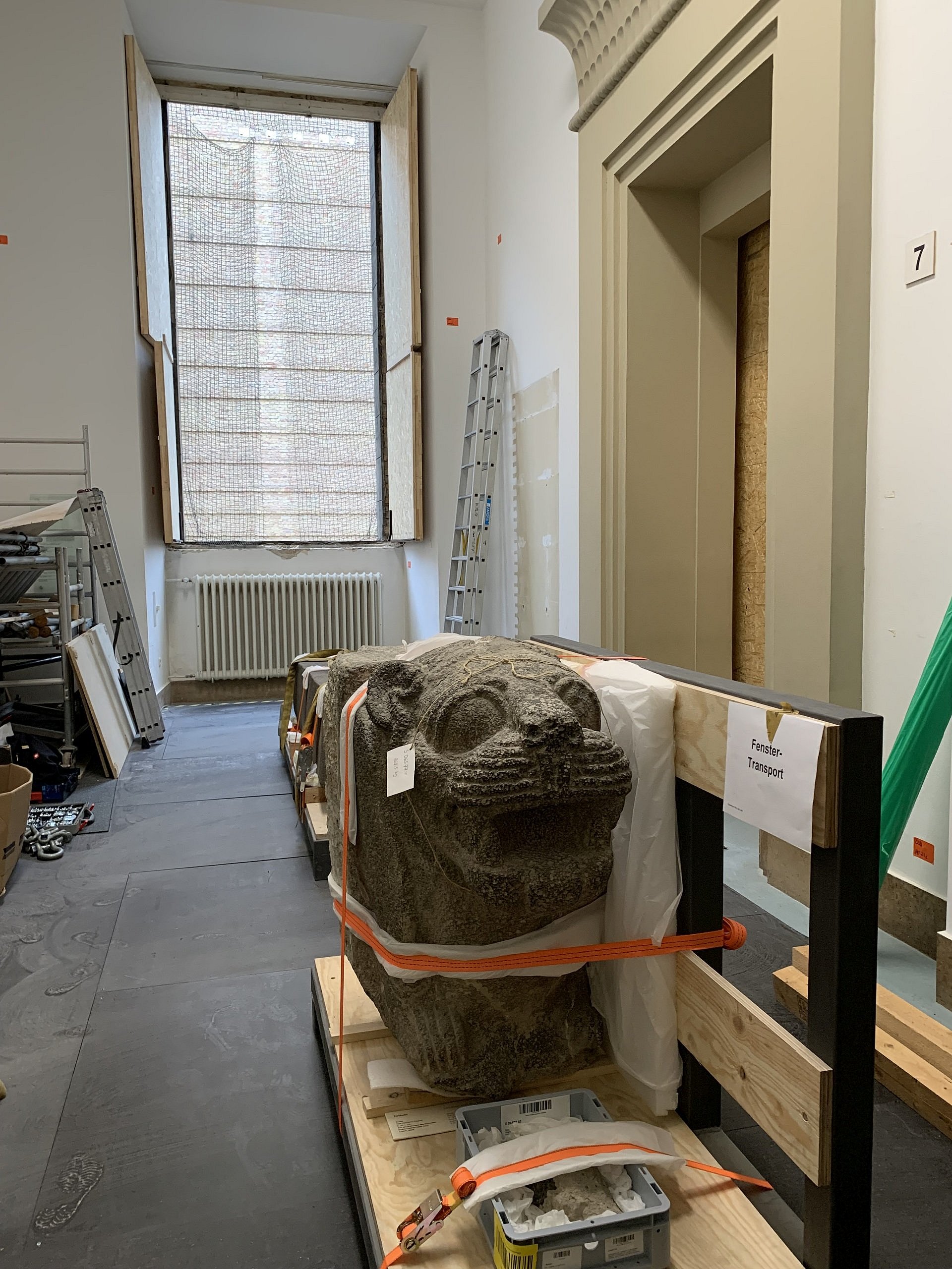 Löwenstatue auf einer Palette vor einem Fenster