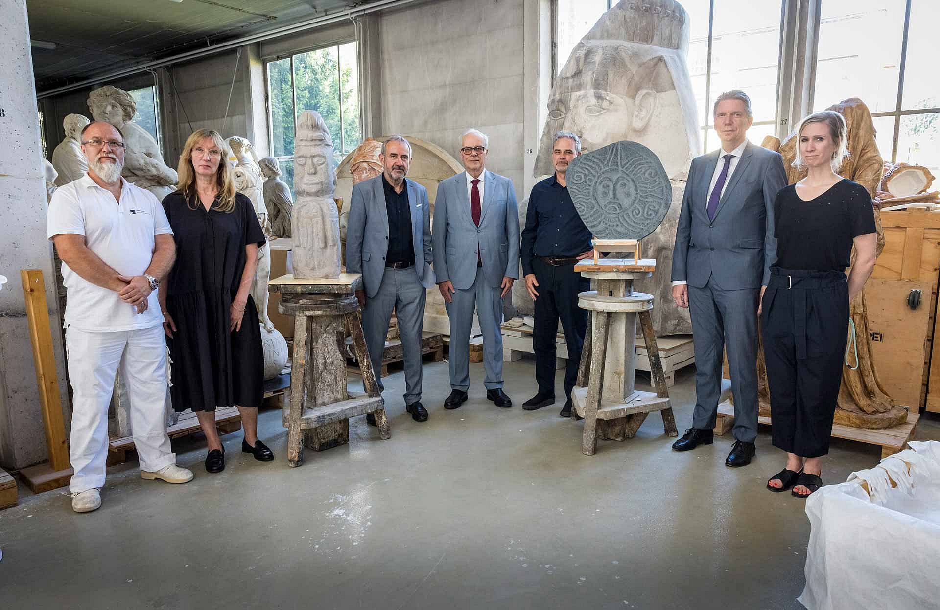 Gruppenfoto in einer Werkstatt neben zwei Gipsabformungen