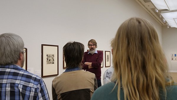 Sven Haase Ein Mann spricht zu einer Menschenmenge in einer Ausstellung