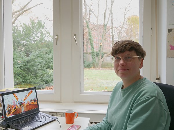 Gesine Bahr Gesine Bahr sitzt an einem Schreibtisch vor einem Fenster
