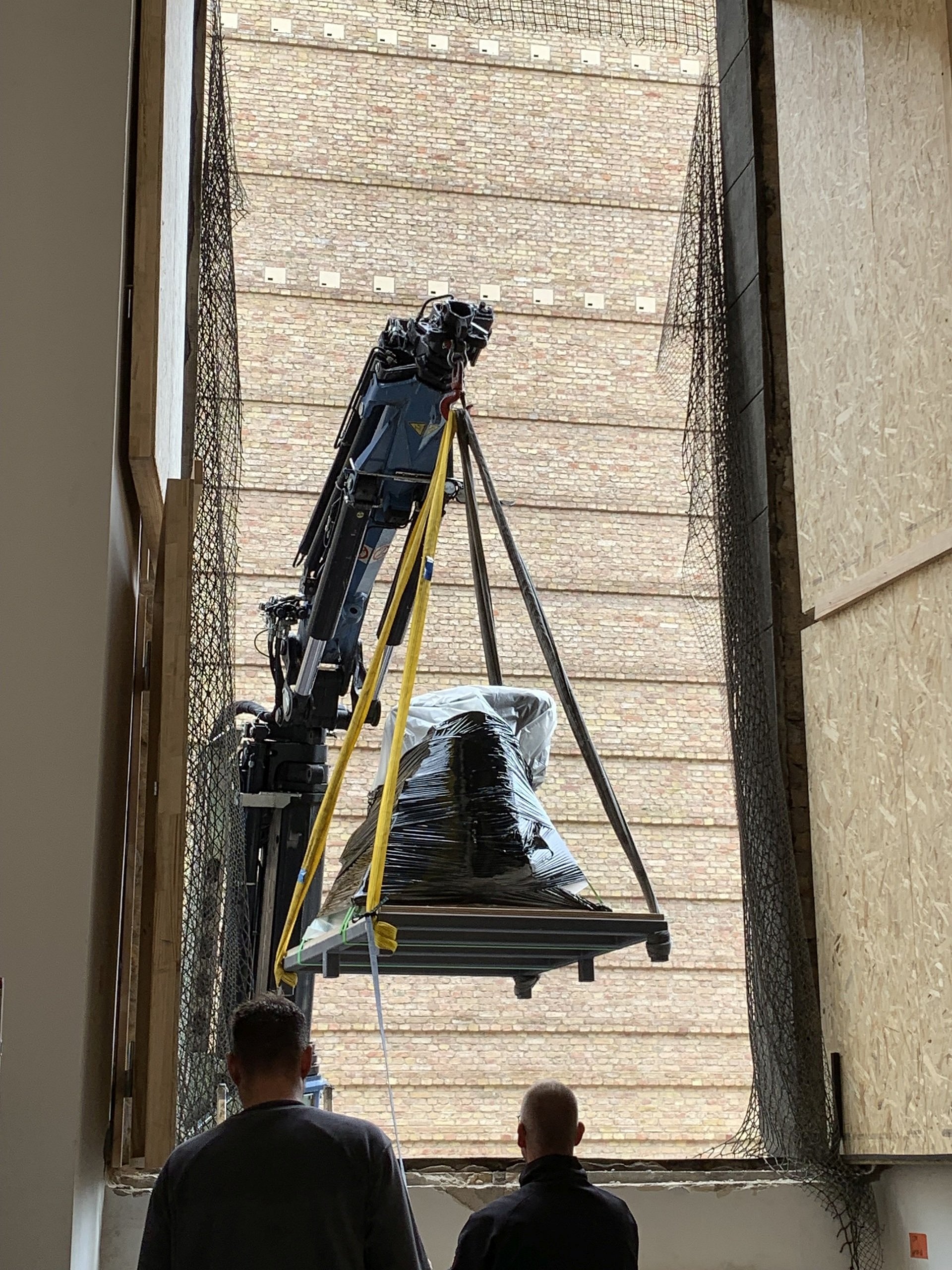 Ein Kran hebt ein verpacktes Objekt aus dem Fenster