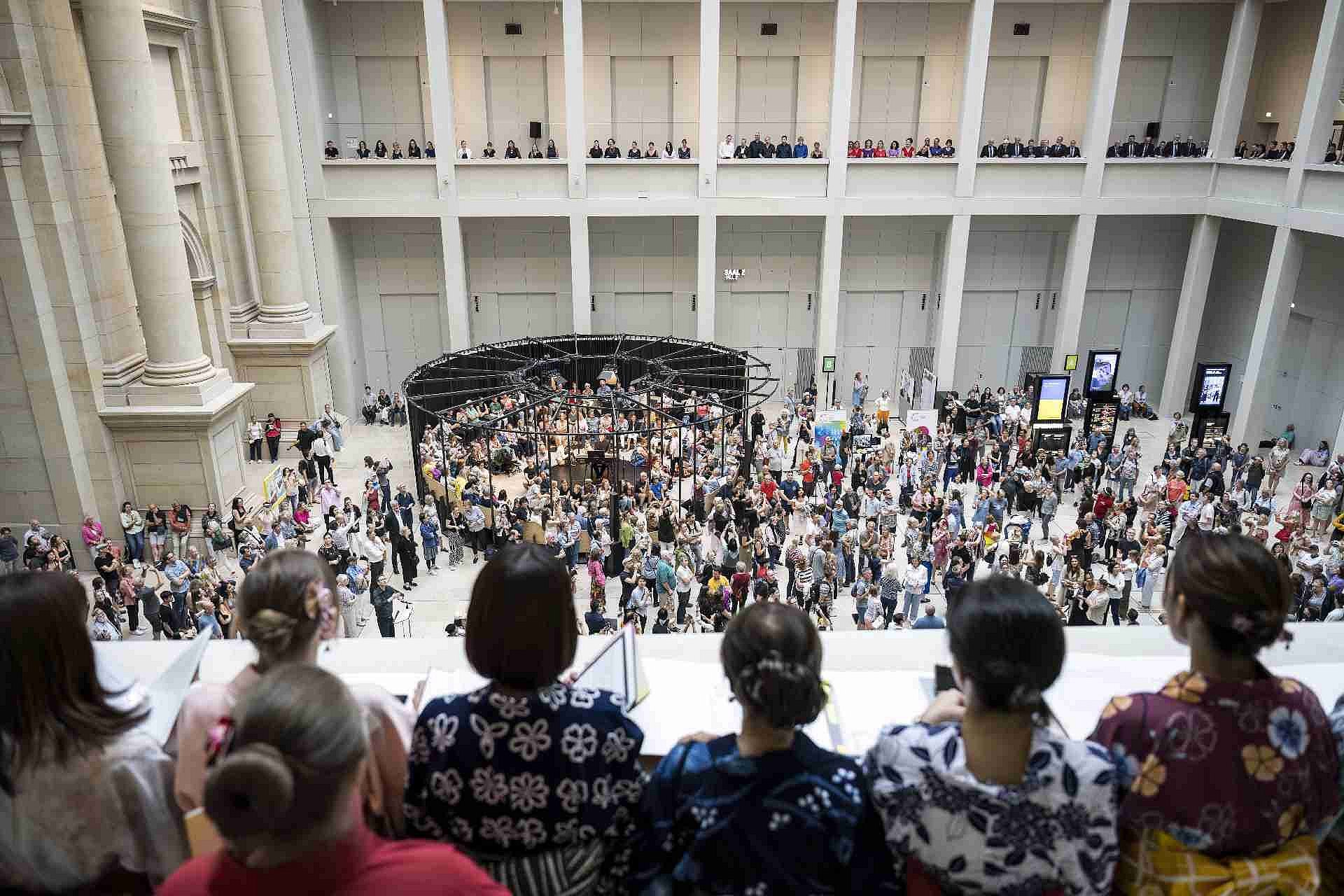 Menschenmassen in einem Lichthof und umliegenden Ballustraden