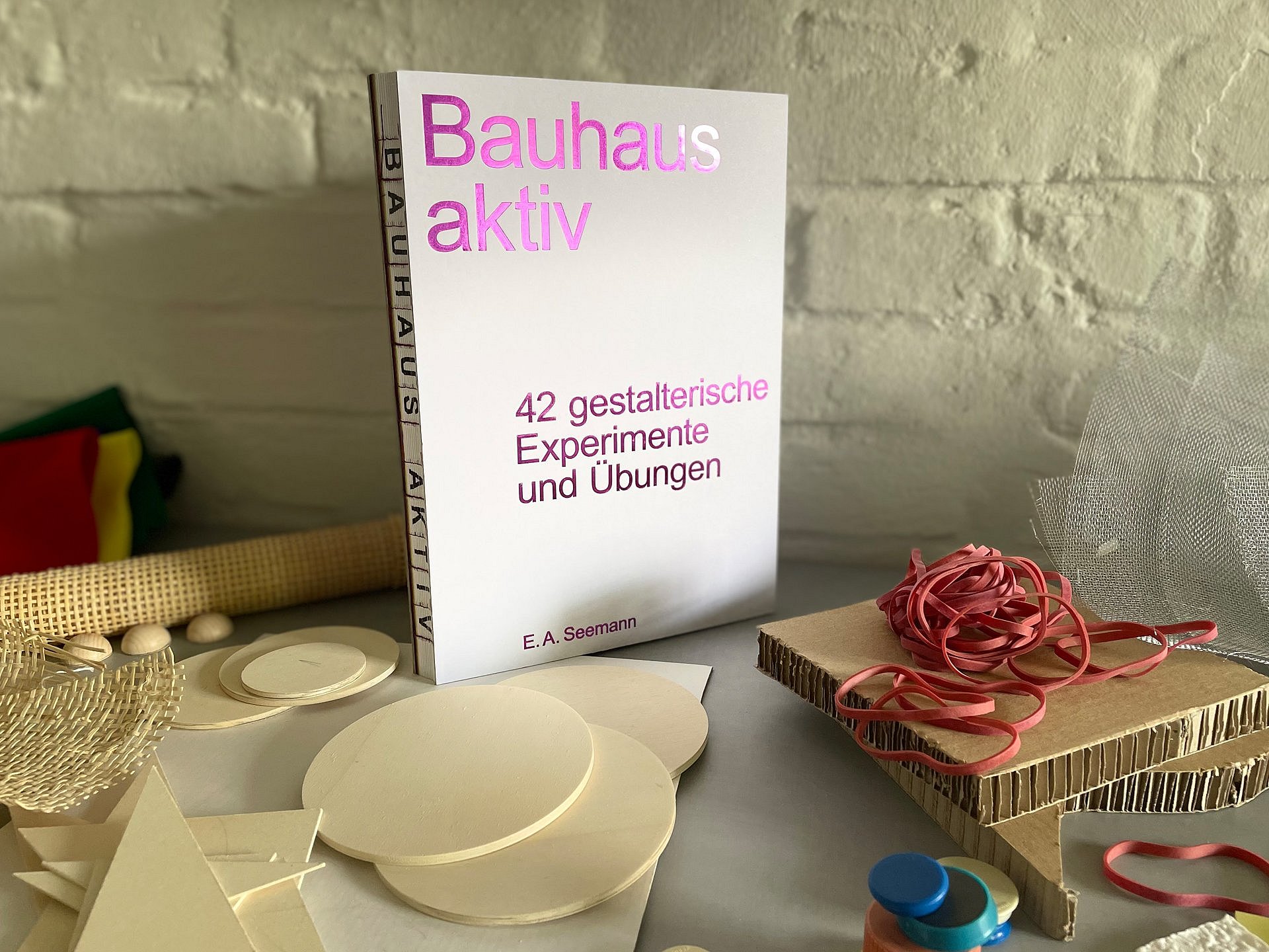 Ein Bauhaus-Buch steht auf einem Tisch voller Bastelmaterialien