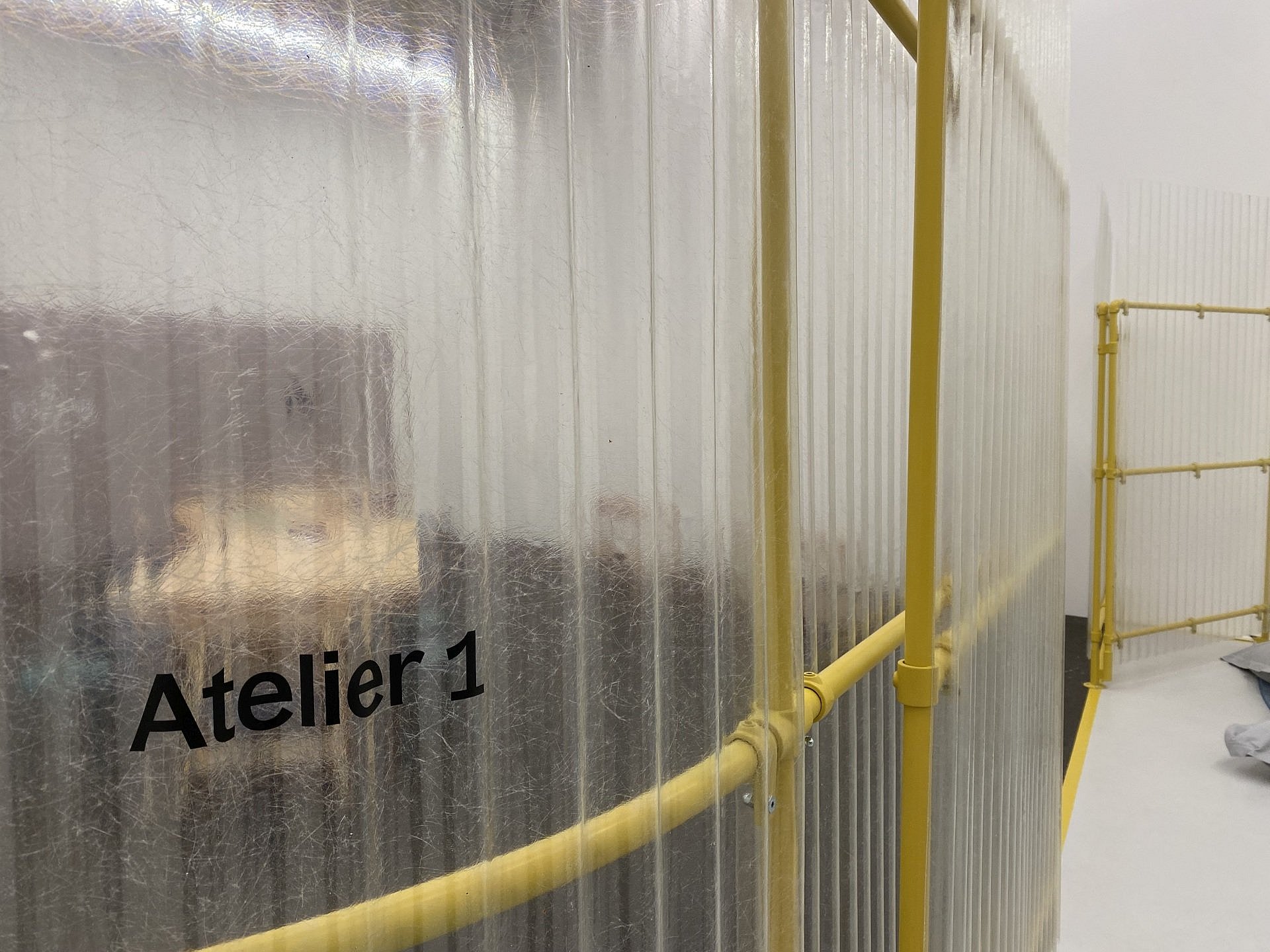 Eine durchsichtige Plexiglaswand mit der Aufschrift "Atelier 1"