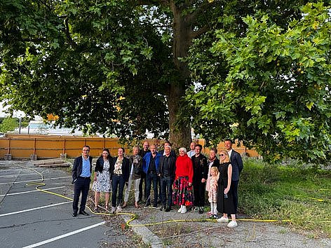Eine Menschengruppe posiert vor einem großen alten Baum
