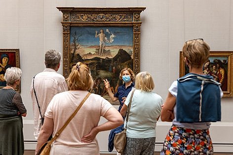 Menschen betrachten ein Ölgemälde mit viel Gartendarstellung