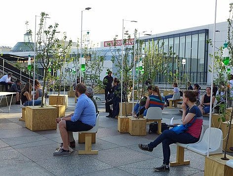 Menschen sitzen auf einem Platz mit Bäumen