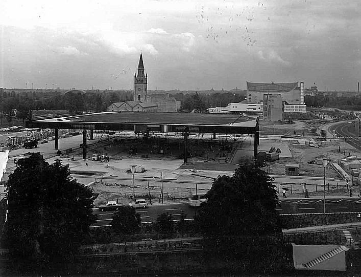 Schwarz-Weiß Fotografie mit Blick auf eine Baustelle in einer Stadt vor wolkenverhangenem Himmel (öffnet Vergrößerung des Bildes)