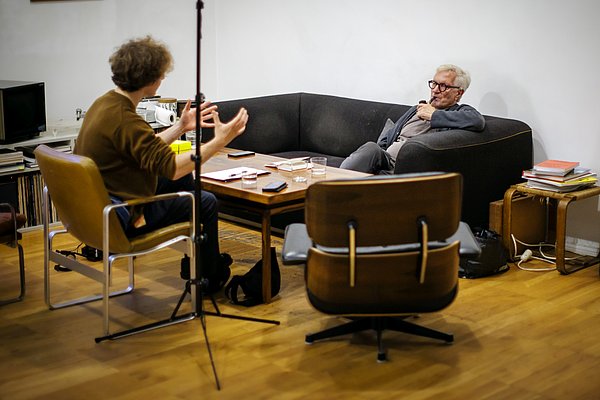 Two people are chatting whilst sitting down.