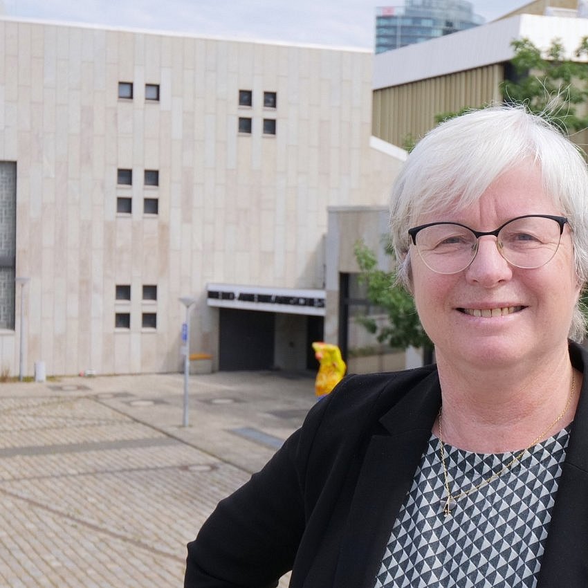 Eine Frau steht vor einem Forschungsinstitut