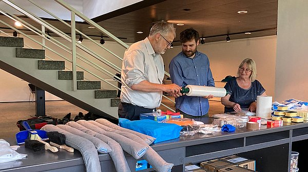 Notfallkoffer Mehrere Personen breiten Gegenstände auf einem Tisch aus