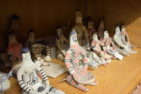 Mehrere menschenähnliche Tonfiguren sitzen in einem Depotregal