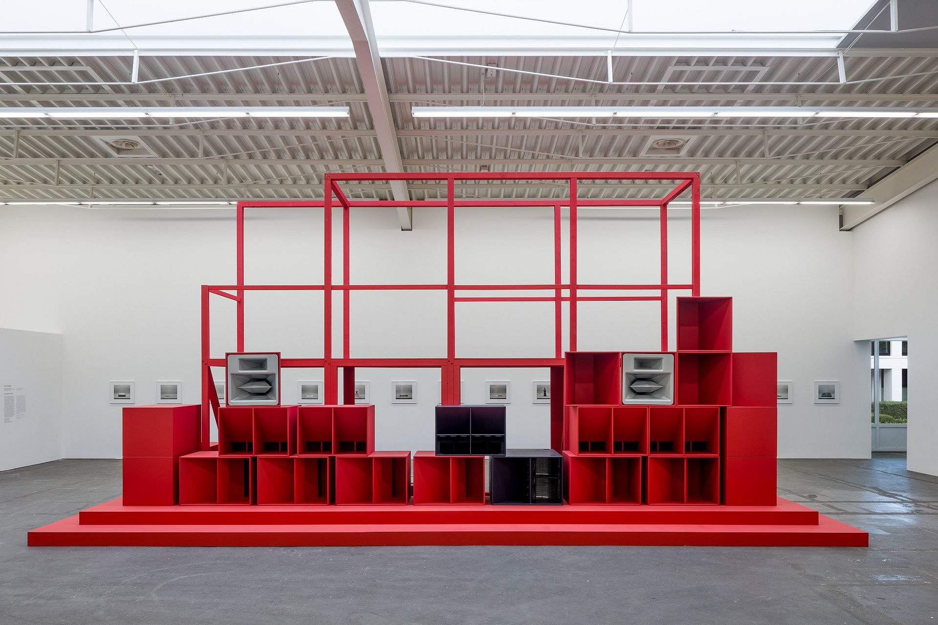 Ausstellungsansicht “Museum in Bewegung. Eine Sammlung für das 21. Jahrhundert” mit einem roten Kunstwerk und Stereoanlagen