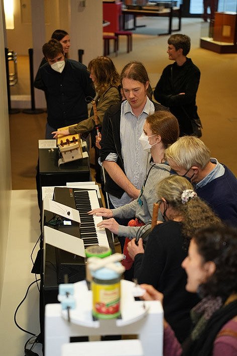 Menschen betrachten Objekte in einer Ausstellung von Musikinstrumenten