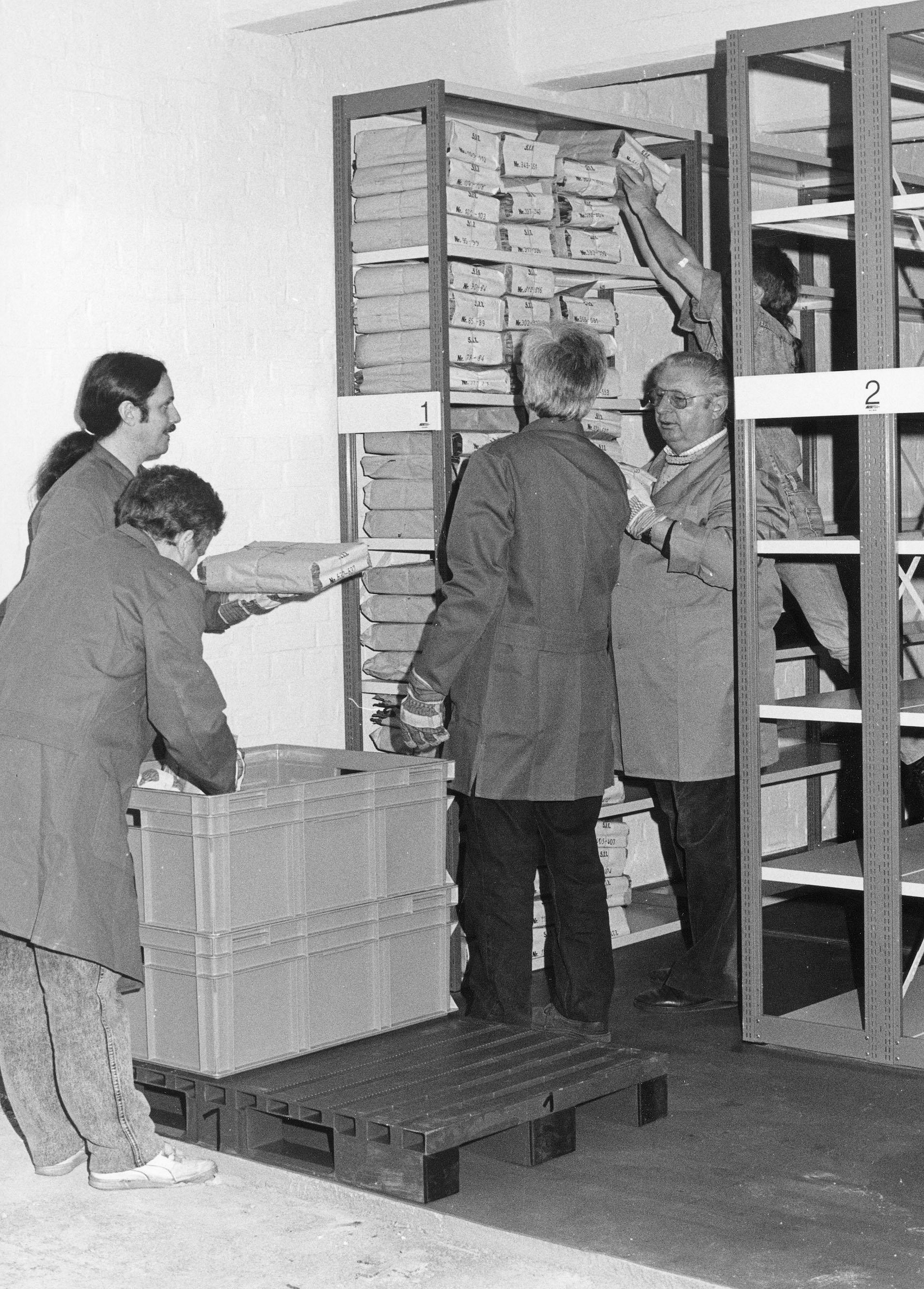 Vier Menschen begutachten ein Regal voller Aktenstapel
