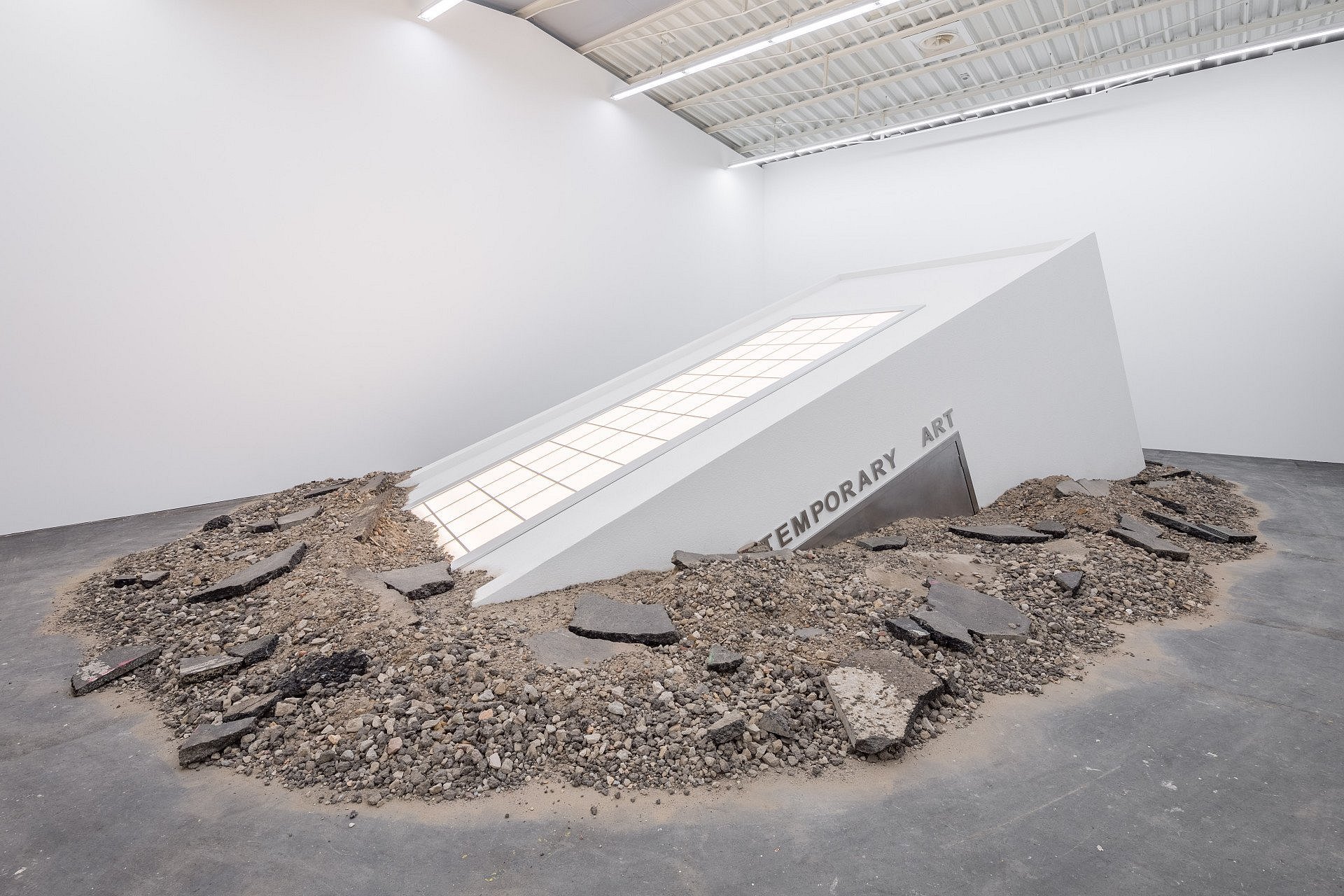 eine gebäudeartige Konstruktion wächst aus dem Boden eines Ausstellungsraums.