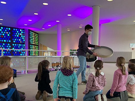 Ein Mann zeigt Kindern ein Instrument