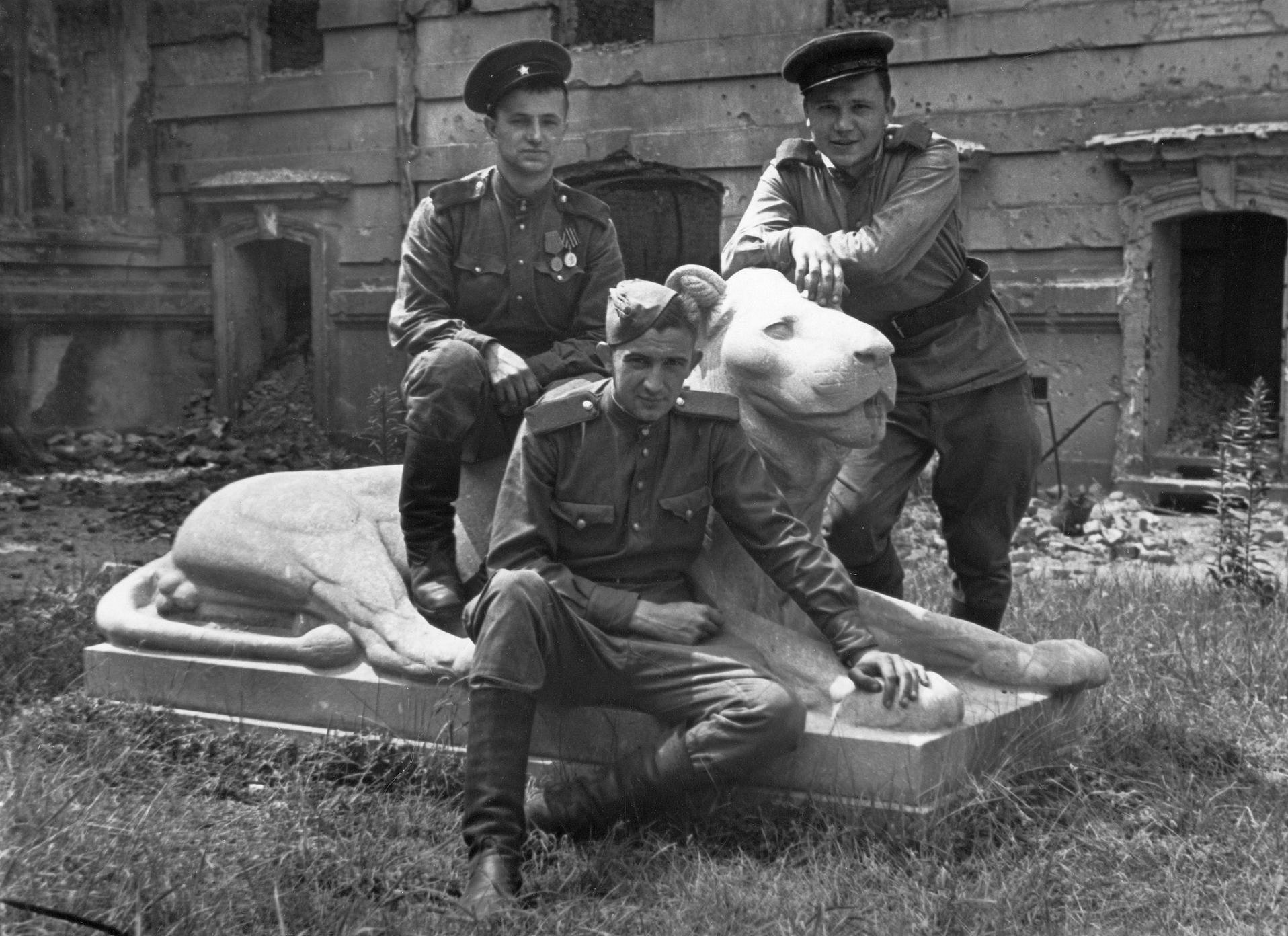 Historisches Foto dreier Soldaten, die auf einer Löwenskulptur posieren