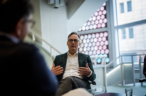 Mann sitzt auf Stuhl in Interviewsituation
