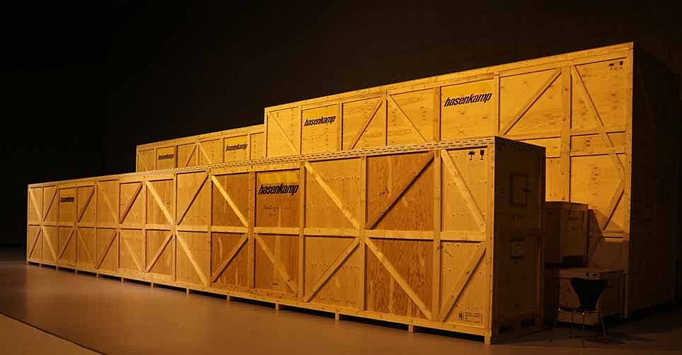 Große Holzkisten stehen in einem schwarzen Innenraum (öffnet Vergrößerung des Bildes)