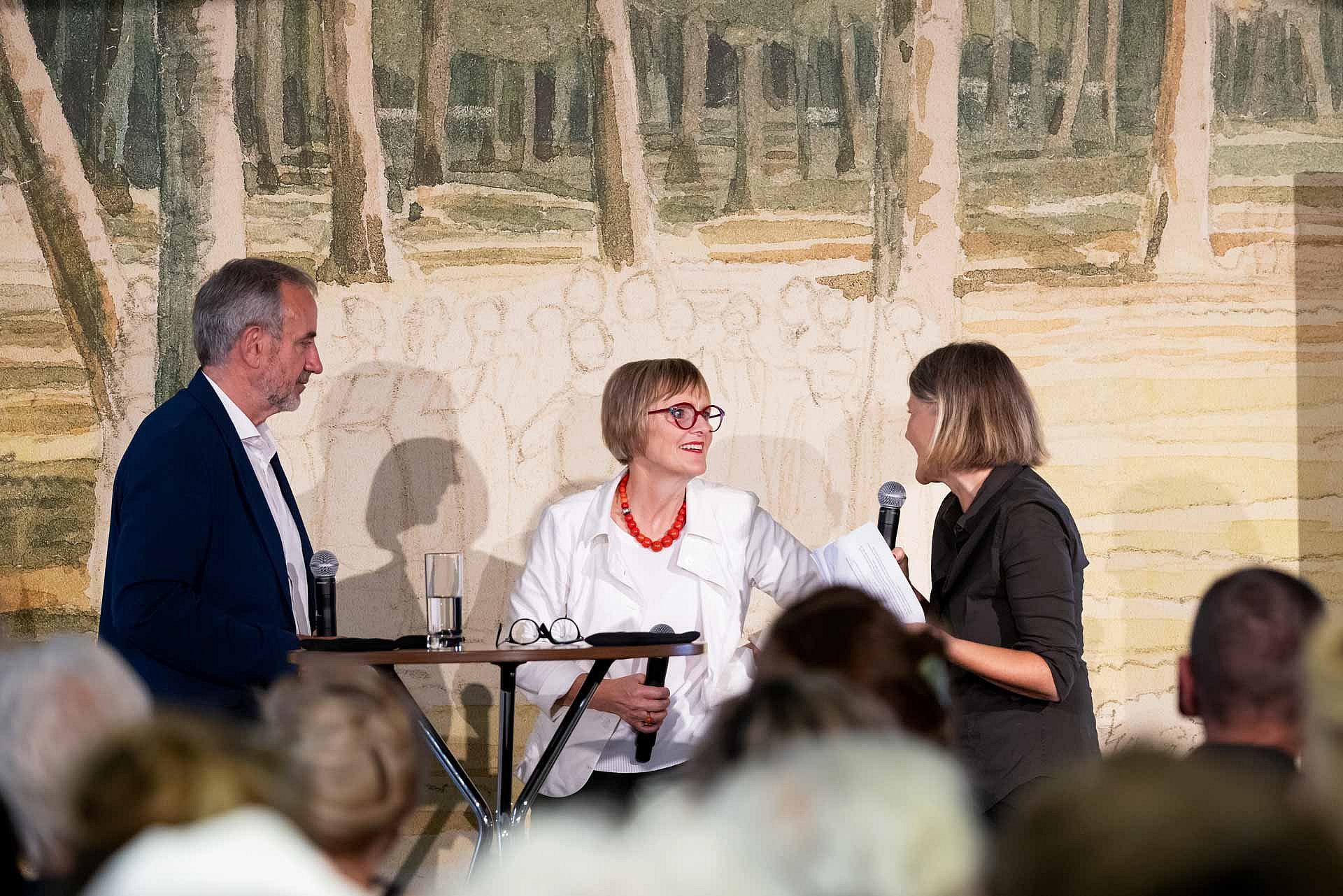 Drei Personen stehen auf einem Podium