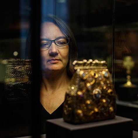 Eine Frau betrachtet ein Reliquiar in einer Vitrine