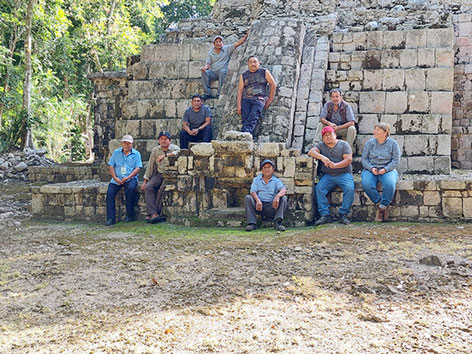 Menschen posieren vor einem historischen Steingebäude im Dschungel