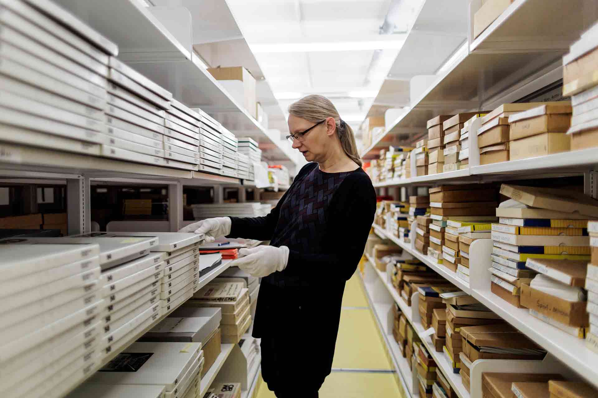 Eine Frau steht zwischen zwei Regalen mit Archivalien