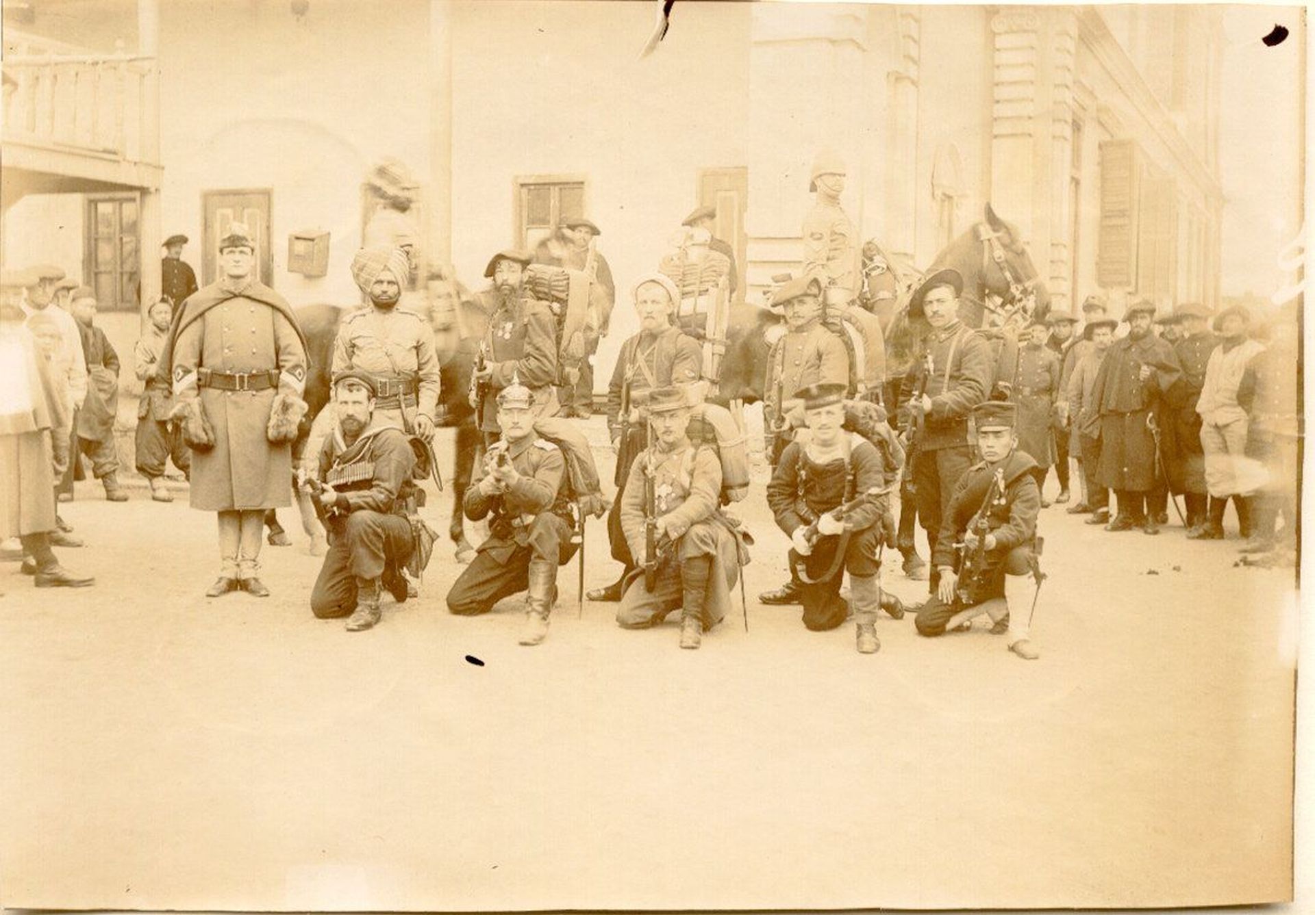 Eine Gruppe von Soldaten verschiedener Länder in Uniformen des frühen 20. Jahrhunderts posiert für ein Foto. 