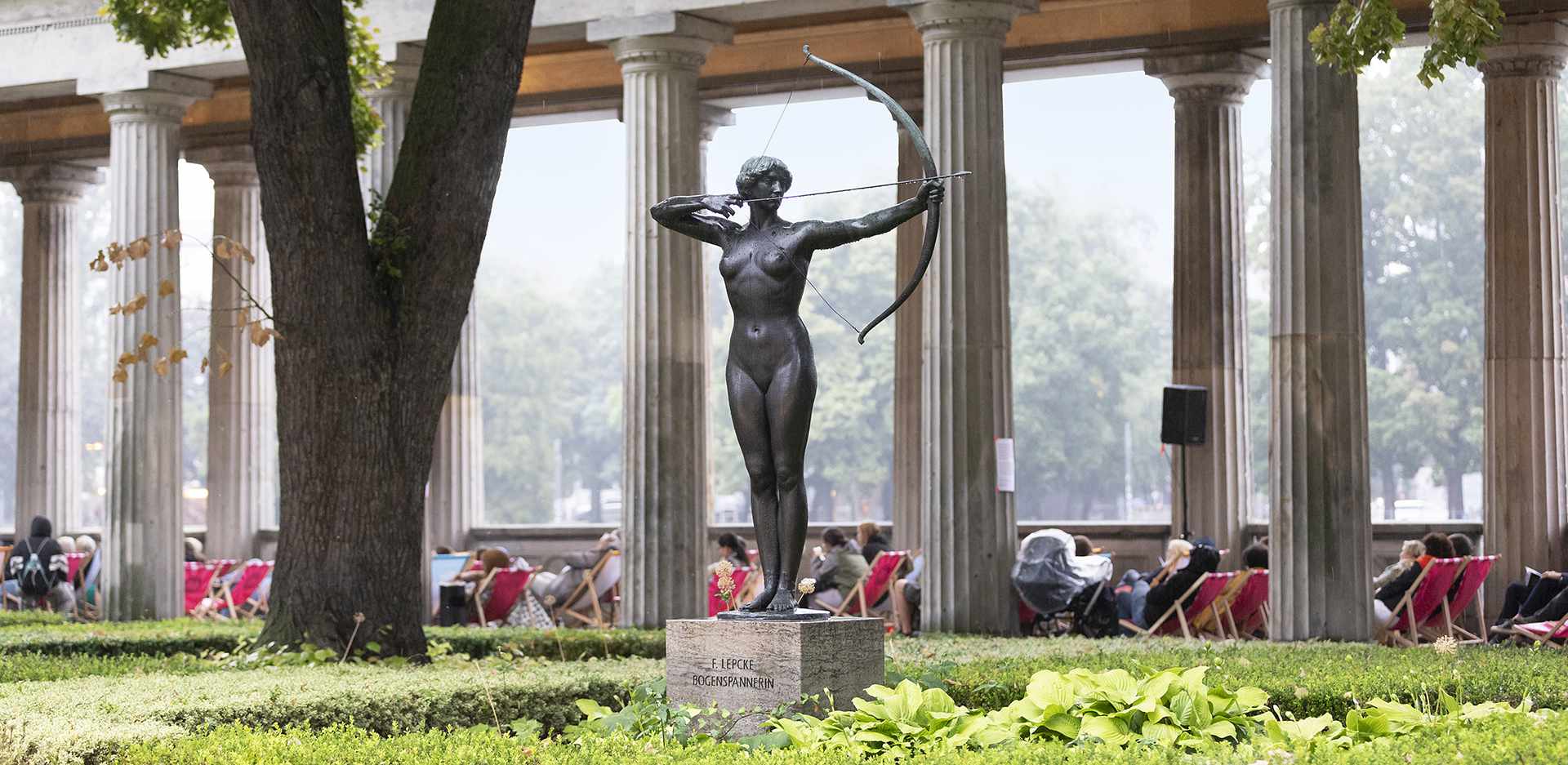 Statue einer Bogenschützin vor Kolonnaden