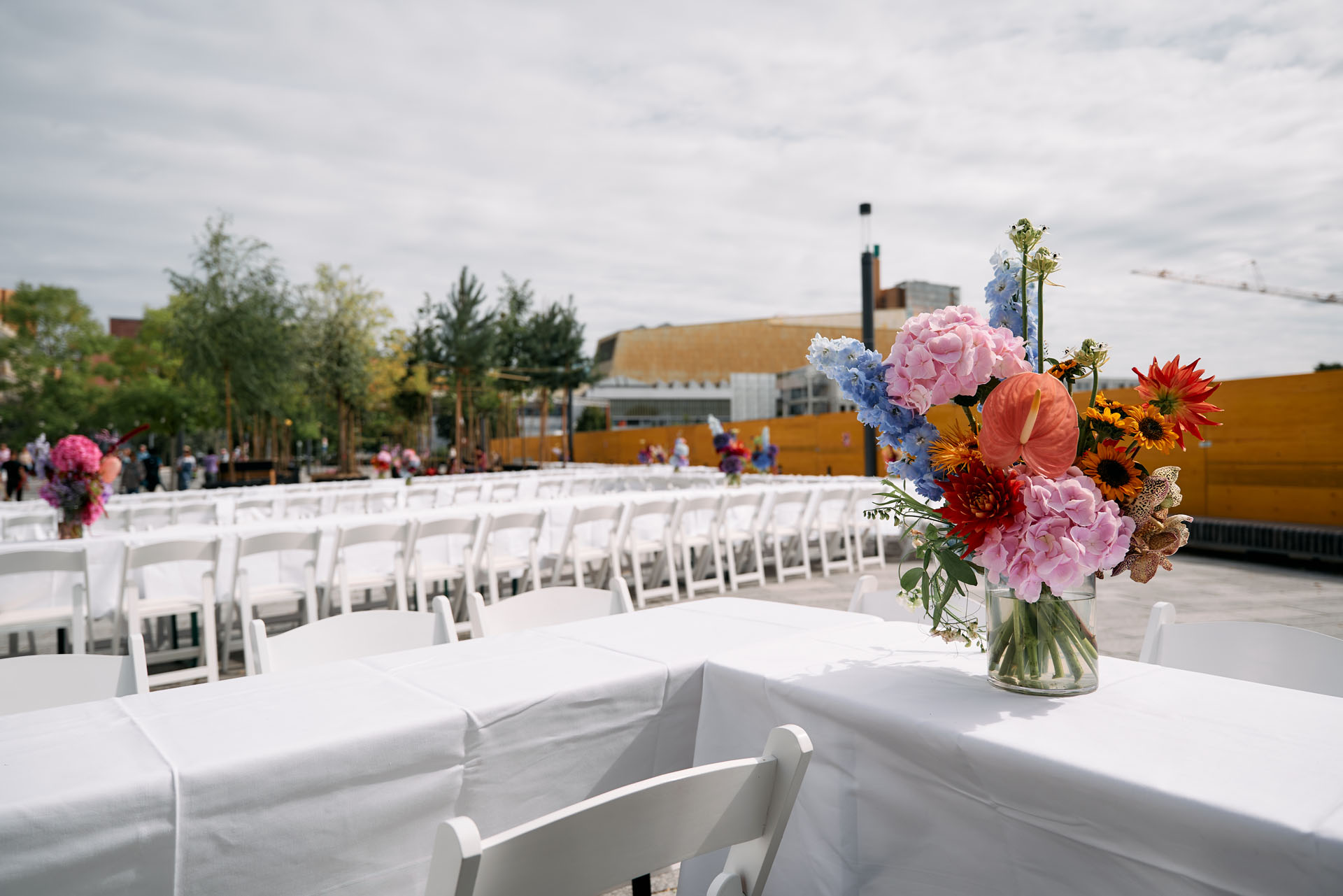 Leere Tafel mit weißen Tischtüchern und Blumenstrauß unter freiem Himmel